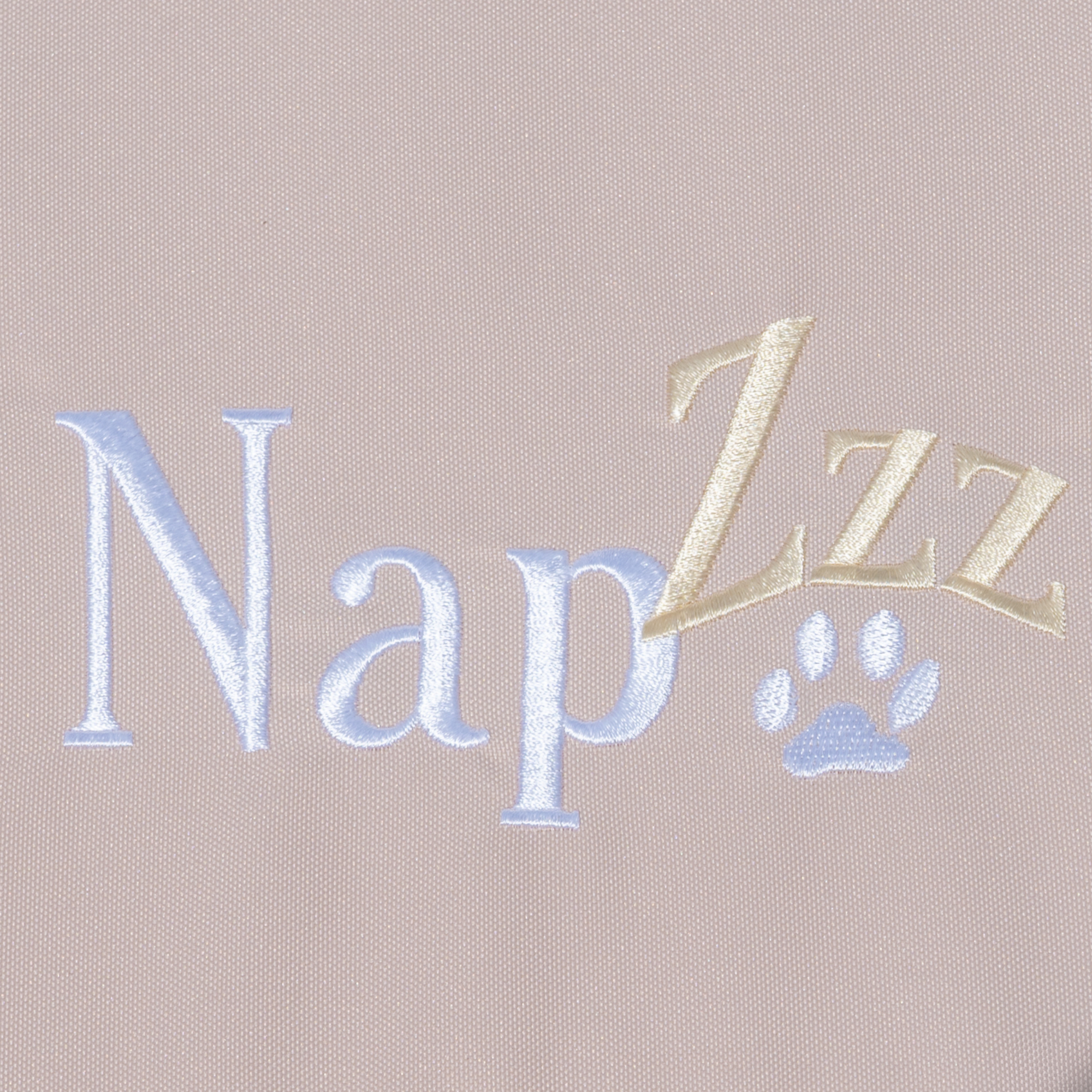 Napzzz benchkussen waterafstotend oxford stof in creme kleur op witte achtergrond afgebeeld in detail van de stof met napzzz logo. Ideaal voor hondenbenches. Verkrijgbaar in diverse maten voorzien van ritssluiting en schuimrubber matras. 