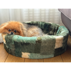 Napzzz bontmand in de stof mixblok groen, meerdere kleuren groen en beige, zijaanzicht met een hond in de mand. Mand gemaakt van stevig schuimrubberen kern en een uitneembare hoes. Hoes wasbaar op lage temperatuur. Verkrijgbaar van 40 tot wel 120 cm.