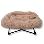 Napzzz ligstoel fluffy beige in langharig imitatiebont in vooraanzicht. Geschikt voor kat en hond. Metalen frame is inklapbaar en voorzien van afneembaar mand/kussen met opstaande rand. Anti slip punten op frame.