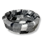 NapZZZ ovale bontmand in de kleur mix blok zwart grijs, foto van de voorkant en heeft verschillende tinten, hondenmand en kattenmand, imitatiebont. Verkrijgbaar van 40 tot wel 120cm. Geschikt van kitten tot zeer grote honden. Stevige schuimrubberen kern met uitneembare en wasbare pluche imitatiebonten hoes.